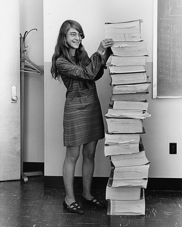 Margaret Hamilton standing next to the navigation software that she and her MIT team produced for the Apollo Guidance Computer
